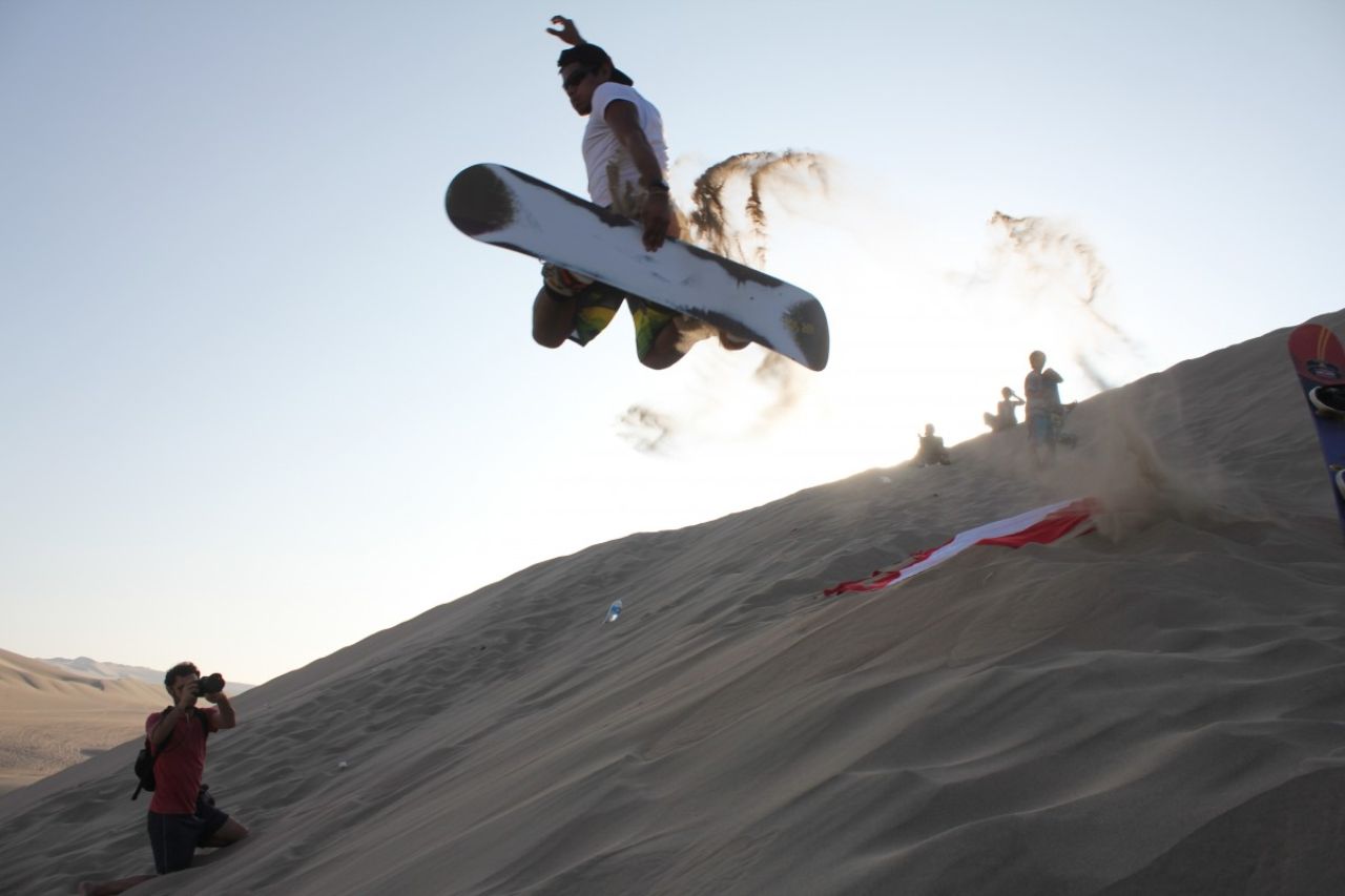 Adventurer jumping off dunes on Peru desert tours
